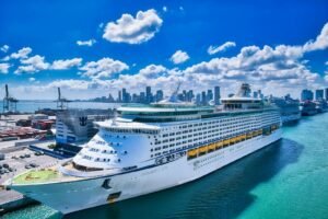 A luxurious cruise ship moored at the bustling Miami port with the city skyline in the background.